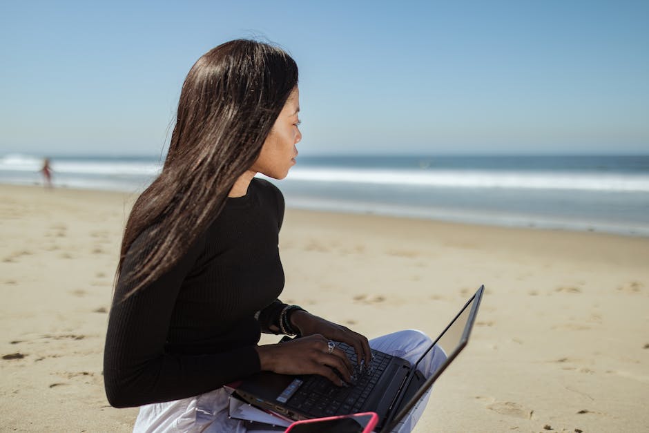 Image of a person working on a laptop while enjoying a beautiful beach sunset