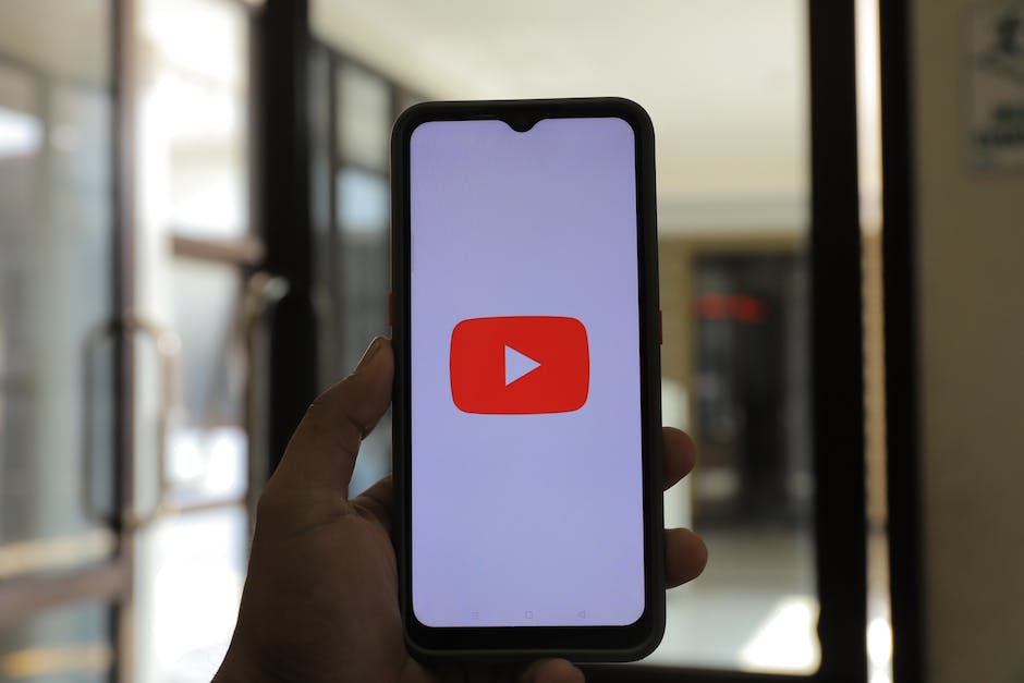 A picture of a person holding up a smartphone showing a blank screen with the YouTube logo on it, representing the anonymity of faceless YouTube channels.