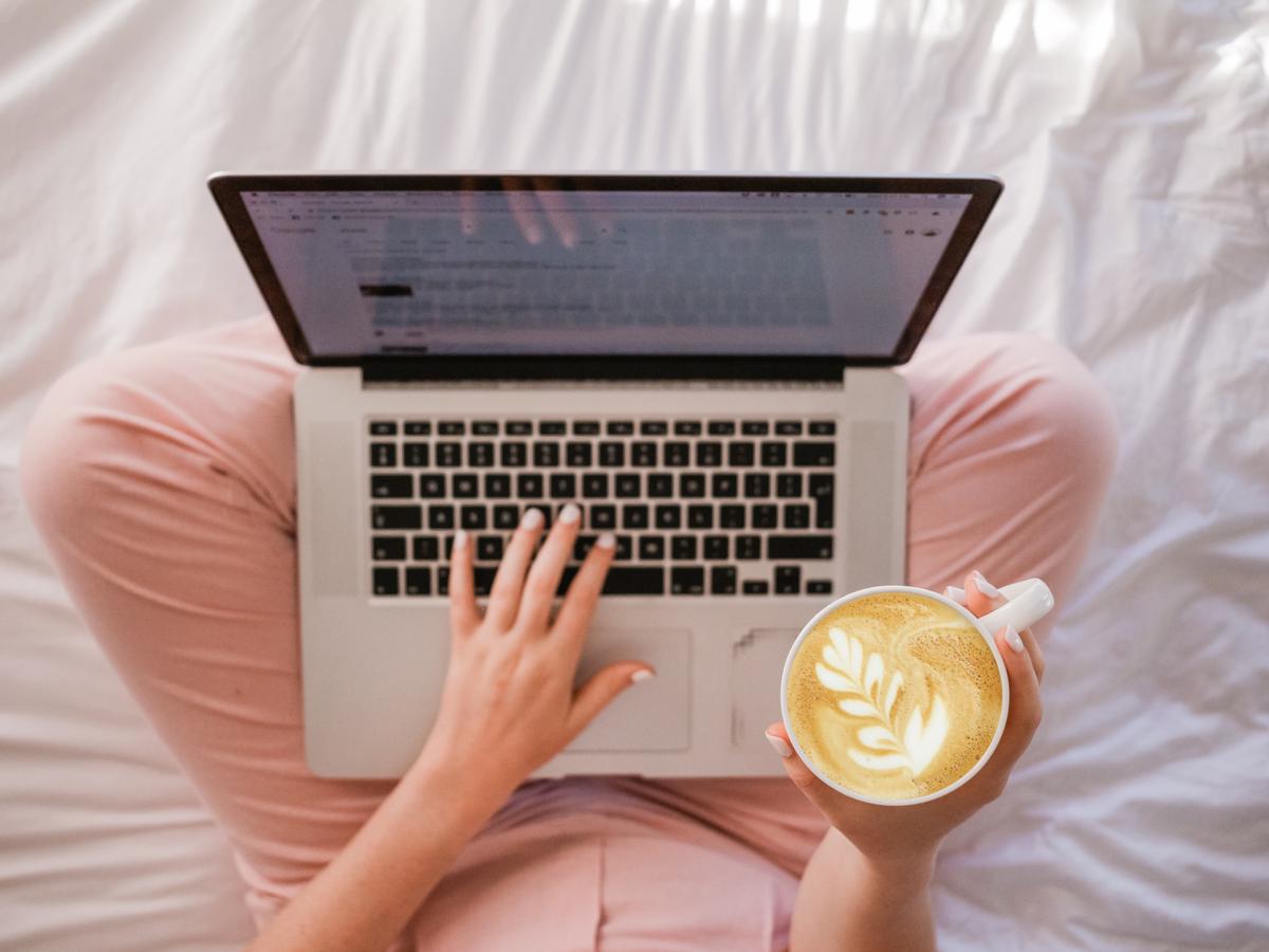 Image of person typing on a laptop with a cup of coffee on the side, representing the importance of high-quality content creation for digital marketing and SEO